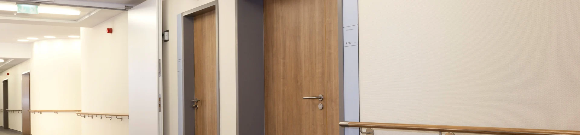 Flur einer Pflegeeinrichtung mit Holztür und Handlauf